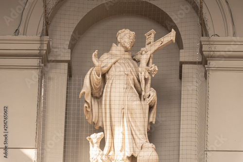 Cuadro en lienzo Frontal view of a historic stone religious statue of a saint with a crucifix ins