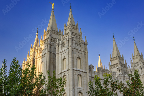 The Salt Lake Temple stands majestically in Temple Square in Salt Lake City, Utah, showcasing stunning Gothic and Romanesque architectural details. Its granite spires rise against a clear blue sky, su
