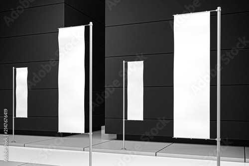 Clean blank white vertical flags for business promotion and marketing messages, perfectly positioned on an urban sidewalk against a modern dark building facade
