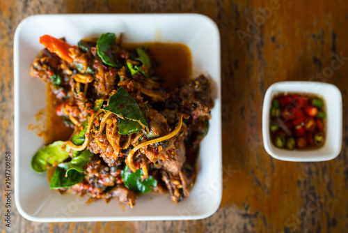 Stir fried catfish with herb and spicy sauce on wooden background. Traditional Thai food