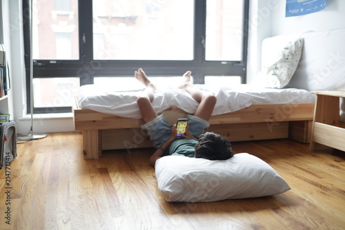 Konstfotografi Young boy enjoying a quiet moment, lying on the floor with feet propped on the b