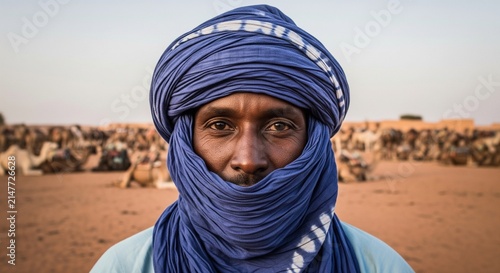 Man in traditional blue turban standing in vast desert landscape under natural light