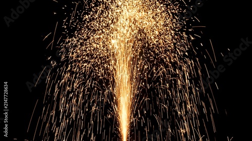 Sparkler fountain fireworks bursting with golden sparks against a black background at night