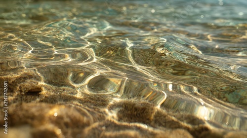 Sunlight patterns on sandy seabed during shallow water tide with clear ripples