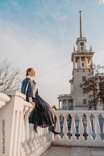 Woman city travel stylish woman sitting on a white stone balustrade near Sochi Marine Terminal with copy space