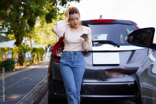 Картината върху платно Asian woman calling insurance agent on smartphone after road accident