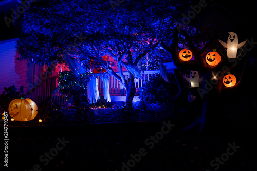 Halloween house decorated with glowing inflatable pumpkins and ghosts purple lights and orange garlands