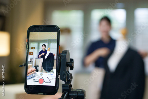 Close-up phone screen front blogger live streaming in her local fashion store, online selling and small business, recording video for social media e commerce and social media concepts.