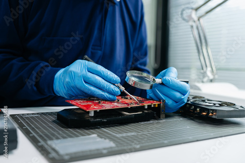 Cuadro en lienzo Professional technician wearing protective gloves inspecting a GPU graphics card at a hardware repair workbench
