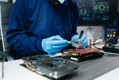 Fotografie Professional technician wearing protective gloves inspecting a GPU graphics card at a hardware repair workbench