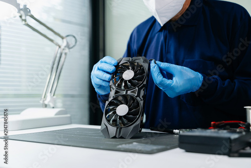 Professional technician wearing protective gloves inspecting a GPU graphics card at a hardware repair workbench. Ideal for building and tech service themes.