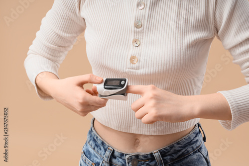 Fotografie Young woman checking her oxygen saturation and pulse rate with a finger pulse ox