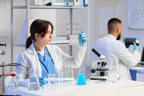 Young chemists with different glassware examining water samples in laboratory