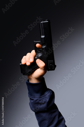 Obraz na płótnie Male hand with gun on dark grey background