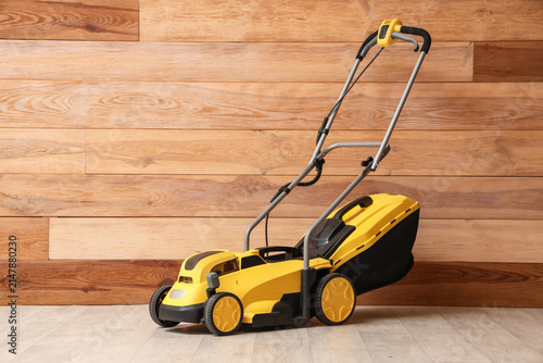 Foto Lawn mower near wooden wall in room