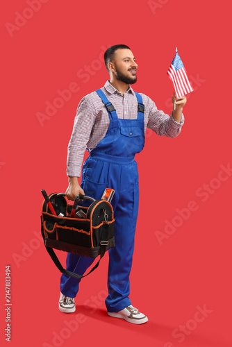 Male worker with USA flag and tool bag on red background. Labor Day celebration