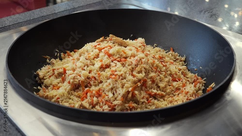 Close-up of a metal cauldron with pilaf in the restaurant kitchen. The traditional national dish pilaf is cooked in a cauldron. Hot side dishes are served in the dining area.