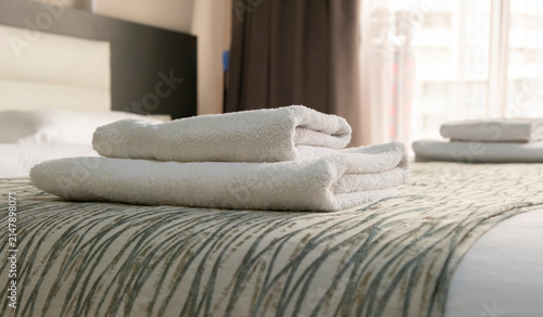 Clean towels stacked neatly on a bed in a hotel room during daylight