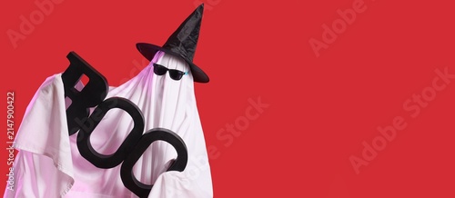 Konstfotografi Funny halloween ghost wearing a witch hat and sunglasses holding a boo sign on a