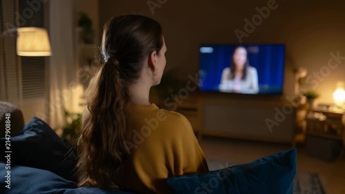 Woman Watching Television News Broadcast Indoors at Night