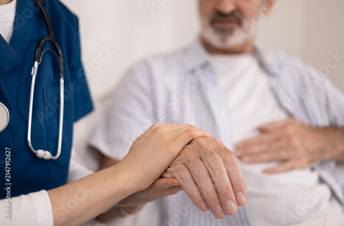 A private healthcare worker for an elderly man uses a digital tablet to monitor the patient's health at home, providing care and checking his physical condition.