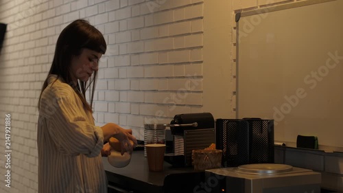 Young woman preparing coffee in office kitchen