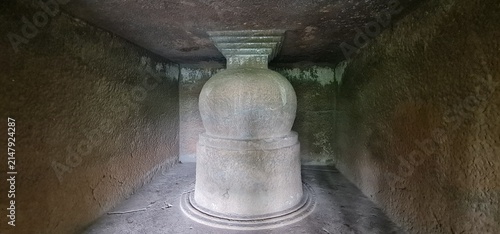 Monolithic Stone Stupa Inside Dimly Lit Cave Chamber at Historic Kuda Caves Archaeology Site
