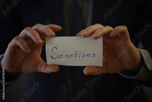 Foto Man showing sanctions word on paper and devastated middle aged caucasian man in