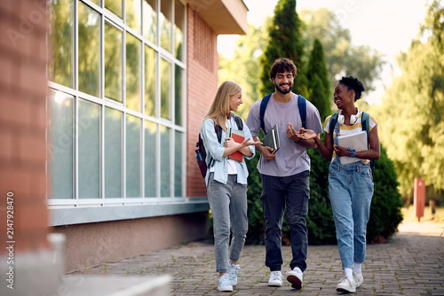 Happy diverse students talking while going on lecture at university.