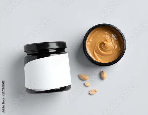 Two jars of creamy spread, one open, with scattered nuts on a light grey background