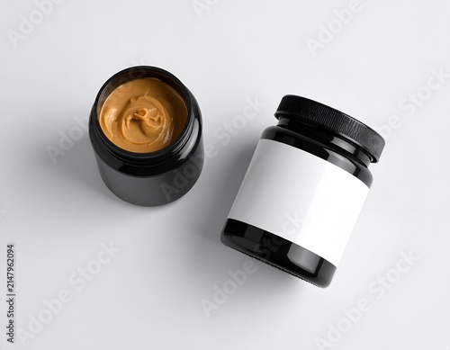 Two black jars on a white surface, one open with creamy contents