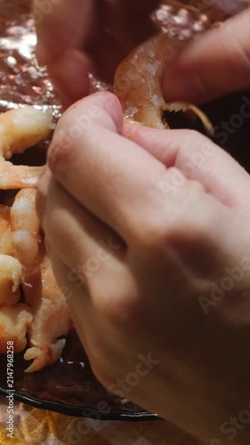 Vertical video. Food prep. Female hands peeling boiled tiger prawns. Eating seafood.