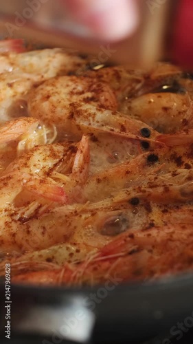 Vertical video. Sprinkling paprika to pan with frying tiger prawns. Shrimps cooking. Food prep.
