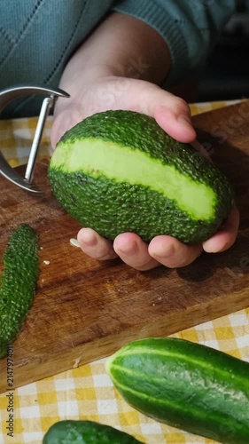 Vertical video. Food prep. Woman peeling avocado for making summer diet salad