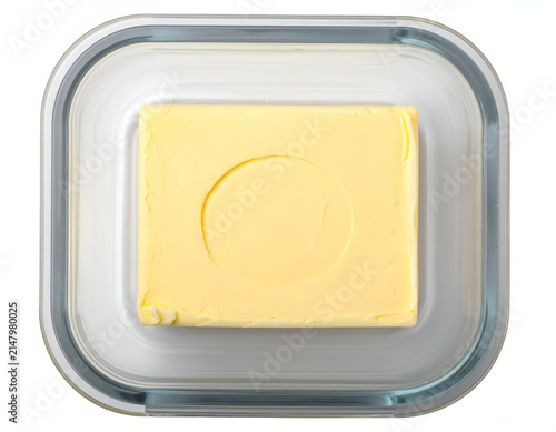 Overhead shot of a glass butter dish containing a rectangular block of yellow dairy butter
