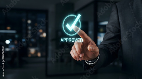 A professional businessman touching a glowing digital hologram of an approved checkmark icon in a dark modern corporate office setting