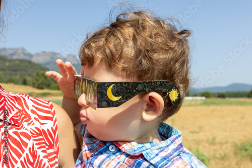 Child watching solar eclipse using protective glasses in Spain