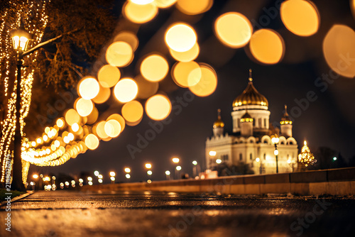 Cathedral of Christ the Saviour glows during a winter night with golden bokeh lights blurred in the foreground creating a magical and peaceful urban scene