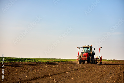 фотографія Farmer driving tractor seeding field, cultivating soil for new crop growth