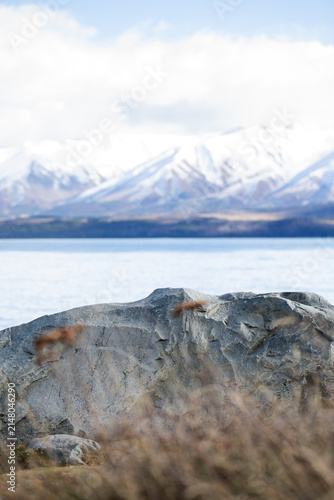 Large natural rock with mountain lake and snowy peaks
