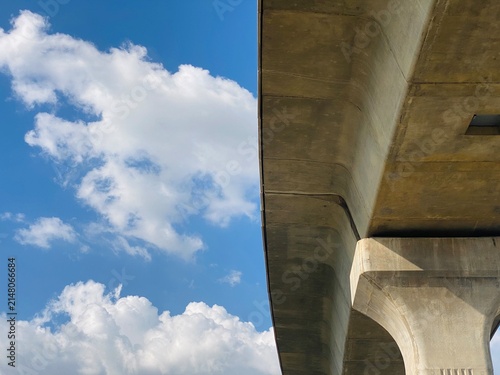 Concrete flyover bridge structure under blue sky with fluffy clouds