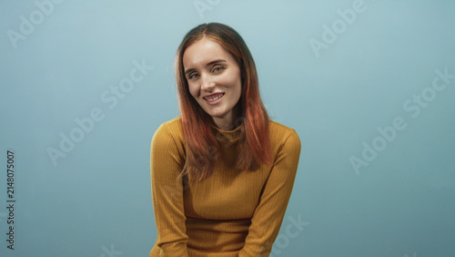 Canvastavla Young woman with face smiling and eyes closed, head tilted and hands clasped in lap in studio; shyness warmth