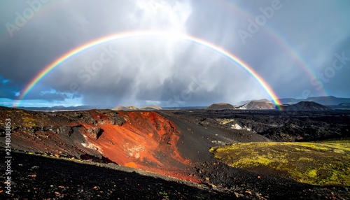 Double Rainbow Arching Over Volcanic Landscape with Red and Black Earth Under Dramatic Stormy Sky