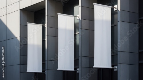Three vertical blank white fabric banners mockup hanging on a modern office building facade