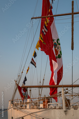 Cuadro en lienzo Flags and sails on a ship during sunset on calm waters