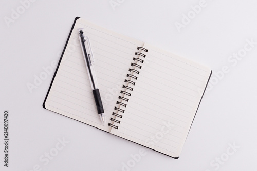 Top view of blank open spiral notebook and black pen isolated on white background
