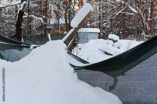 Quadro su tela Snow-covered construction site enclosed by a saggy mesh fencing during a cold wi