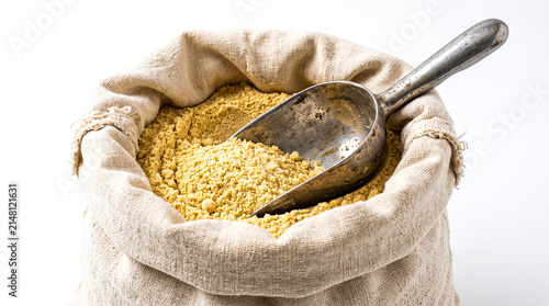 Burlap sack filled with yellow powder and a metal scoop isolated on white background