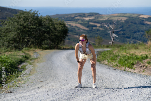 White Woman runner resting on a gravel trail in Galicia, Spain scenic