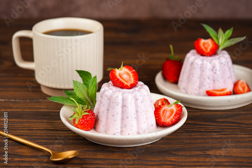 Healthy breakfast or dessert with cottage cheese, chia seeds and fresh strawberry garnish and cup of coffee on a wooden table.